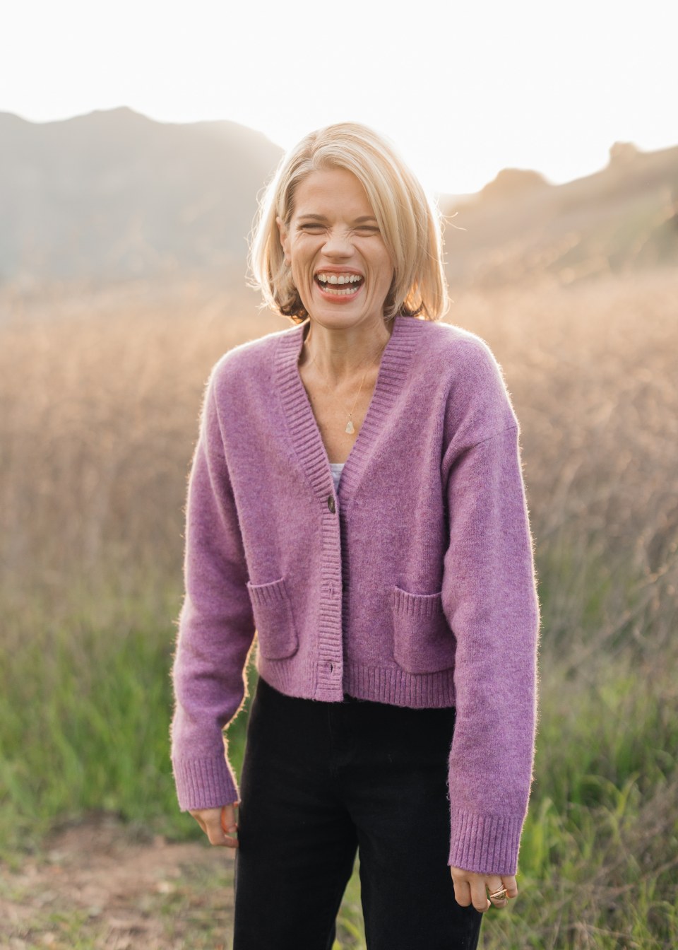Caileen Kehayas Holden laughing in a lavender cardigan in a golden field